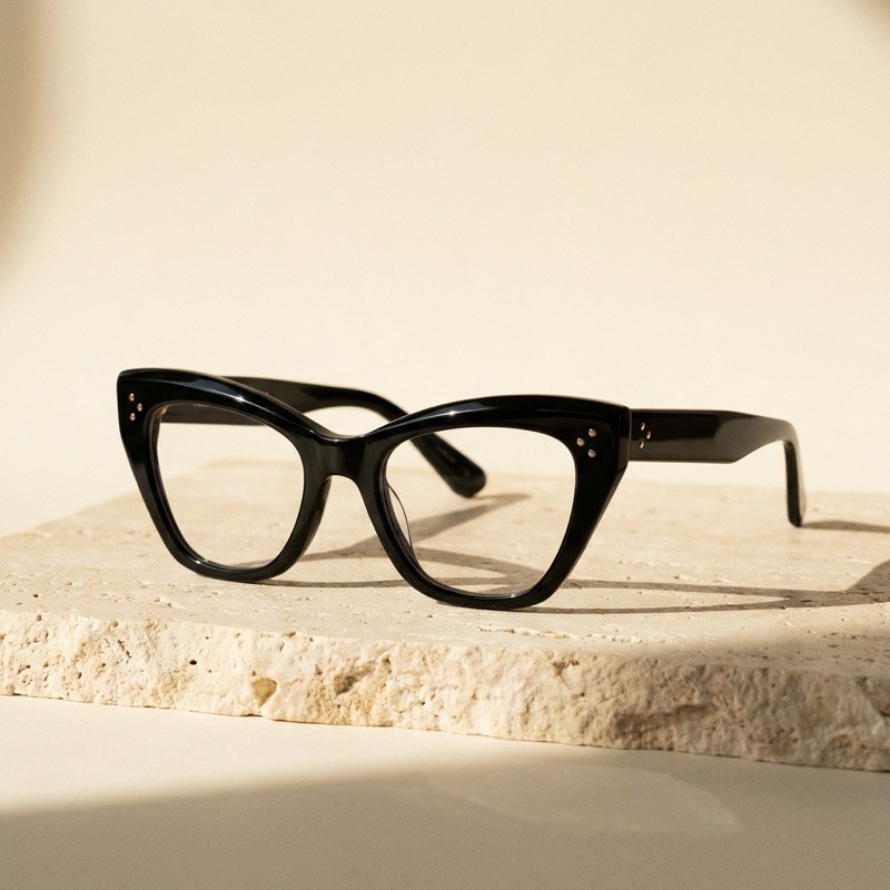 Glossy black acetate cat-eye frames with small gold rivets.