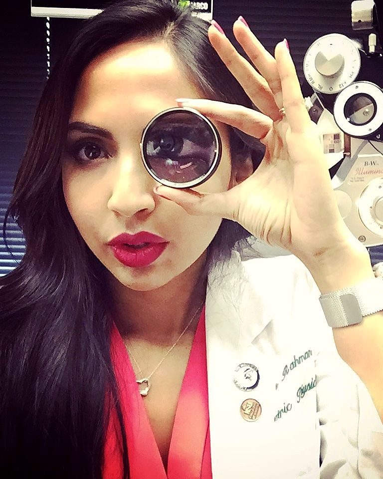 Dr. Rahman holding a trial lens up to one eye in the exam room.